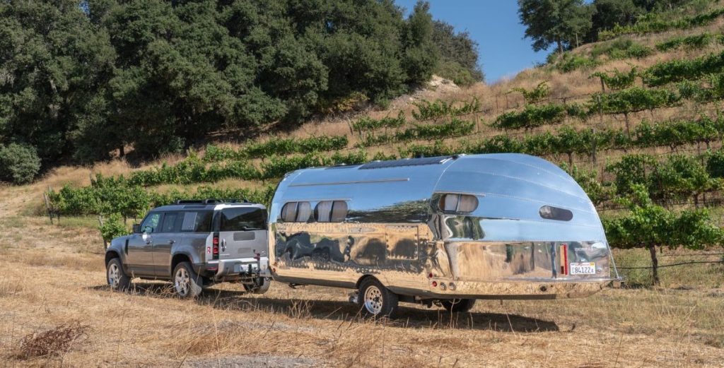 a Bowlus travel trailer being towed by a Land Rover Defender.