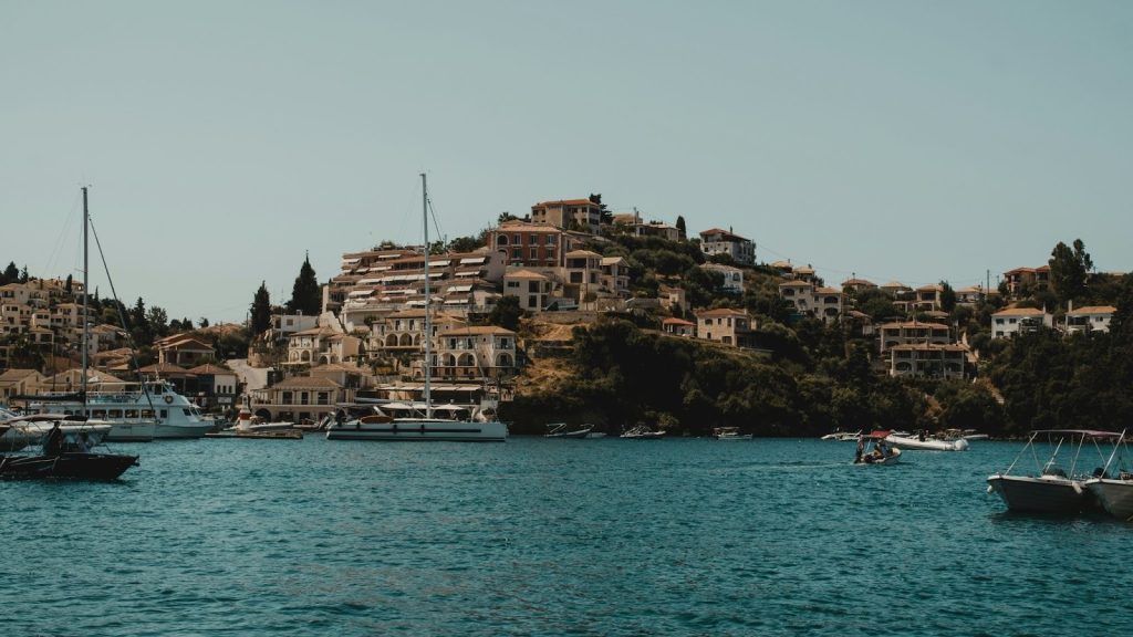 Picturesque Greek or Mediterranean hillside village overlooking a harbor filled with sailboats and yachts.