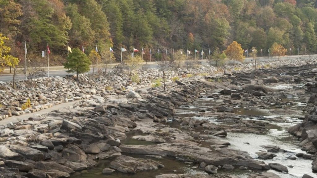 Rocky riverbank with flags along a forest road during autumn in Ocoee Whitewater Center