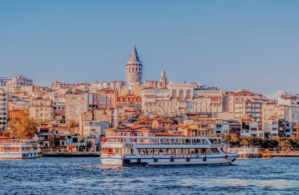 Ferry boat cruising past the historical Istanbul skyline with the iconic Galata Tower dominating the hill.