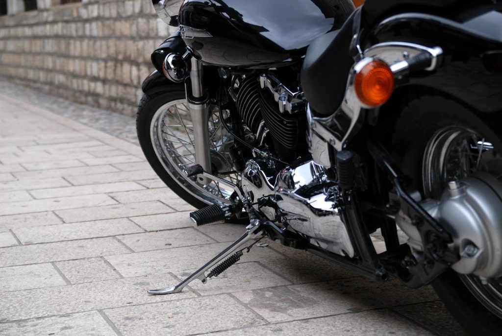 Close-up of a black cruiser motorcycle with polished chrome engine details parked on a stone sidewalk.