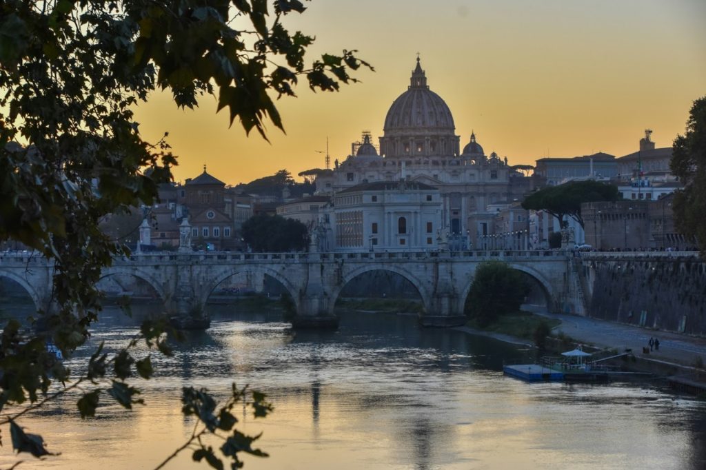 St. Peter's Basilica dome and Ponte Sant'Angelo bridge over the Tiber River at sunset in Rome, Italy.