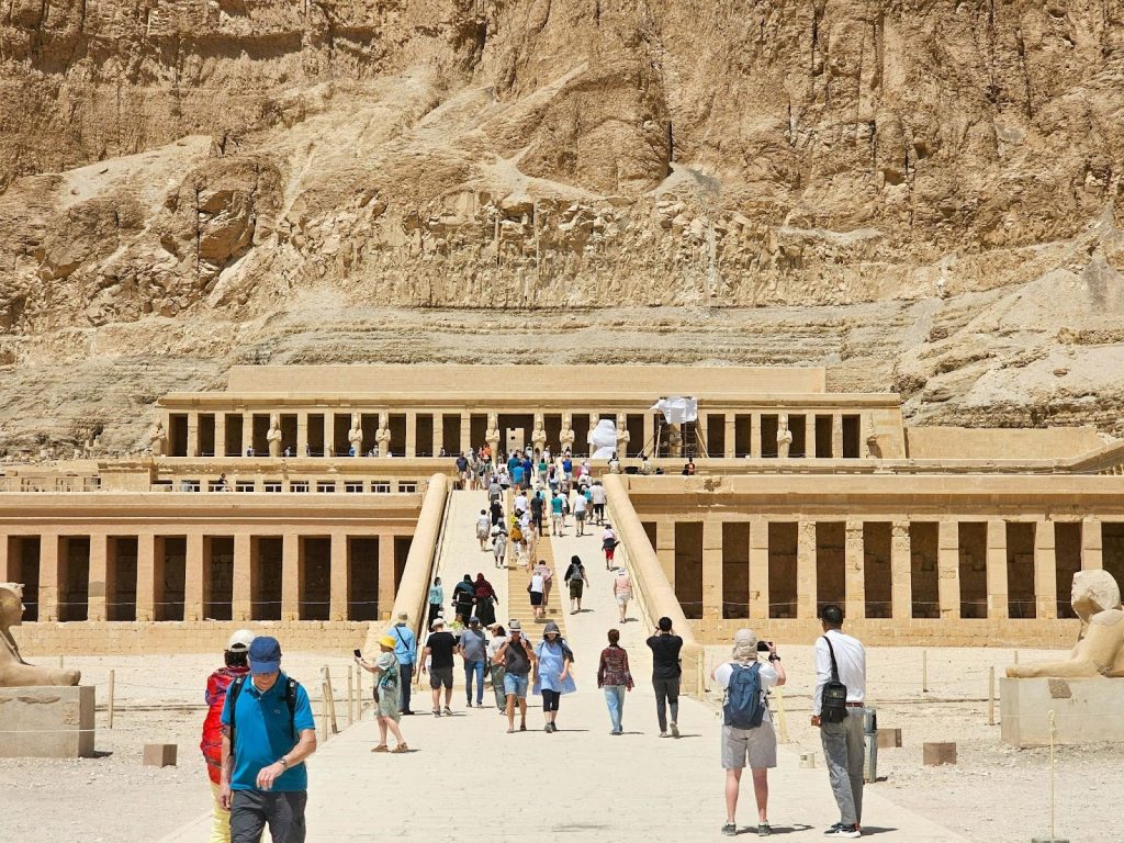 Tourists walking up the central ramp toward the ancient terraced Temple of Hatshepsut at Deir el-Bahari, Egypt.