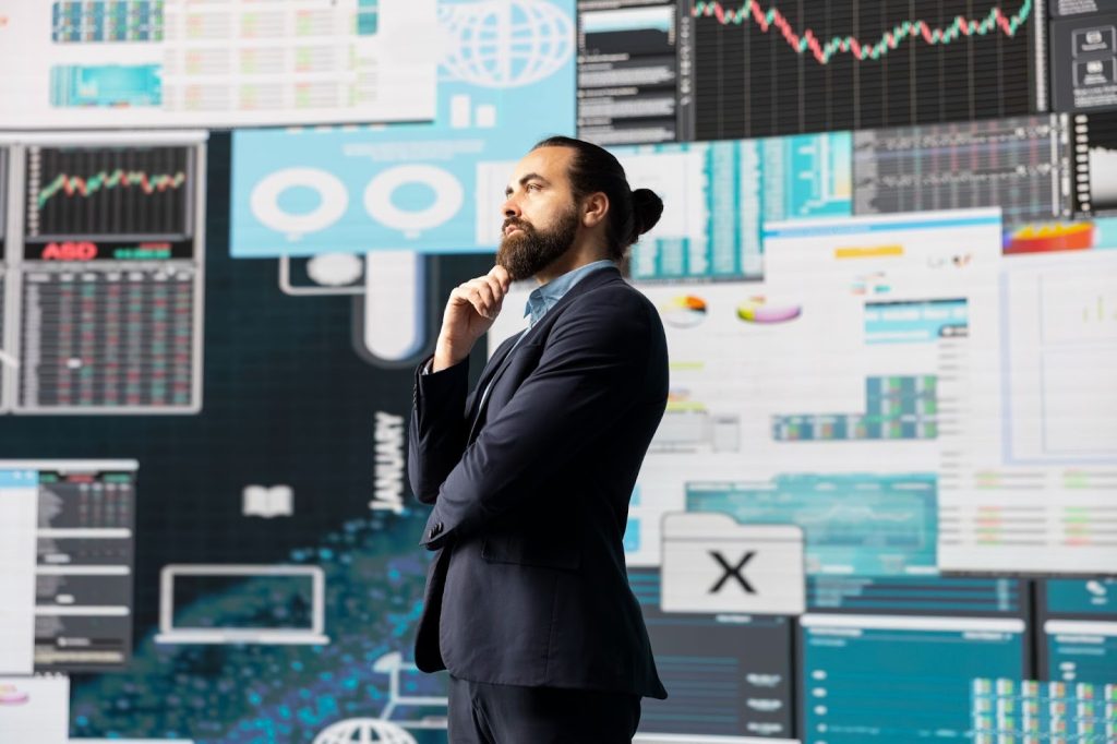 Businessman in a suit thoughtfully analyzing complex financial data and stock market charts on a digital display.
