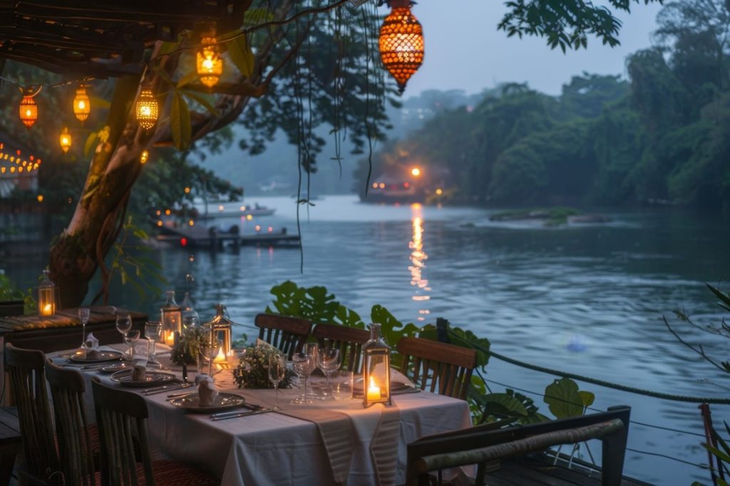 Romantic riverside dinner table set with candles and lanterns under hanging trees at twilight in River House Restaurant in New Hope