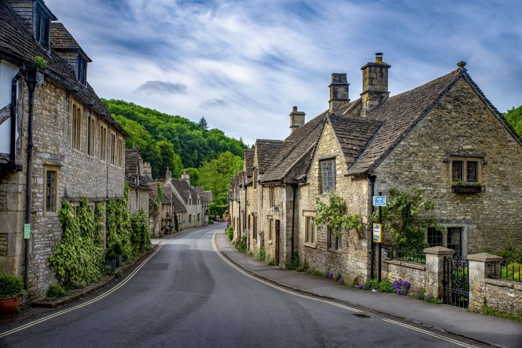 Traditional stone cottages lining a curving road in a picturesque village under a blue sky with wispy clouds in New Hampshire