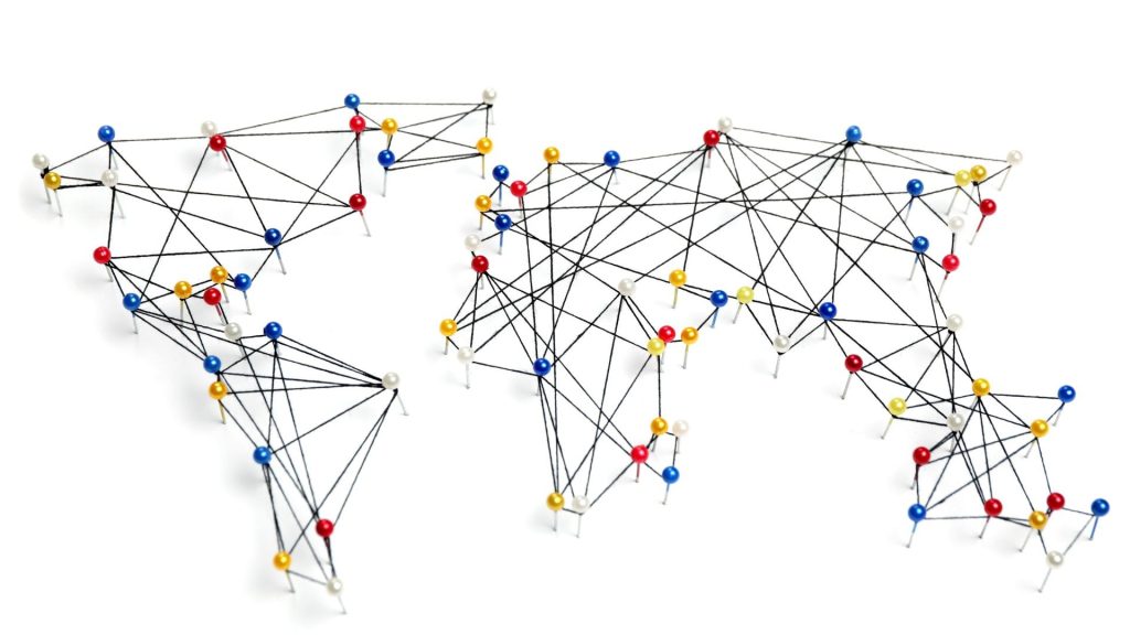 A global map created with colorful push pins and interconnected black strings on a solid white background.
