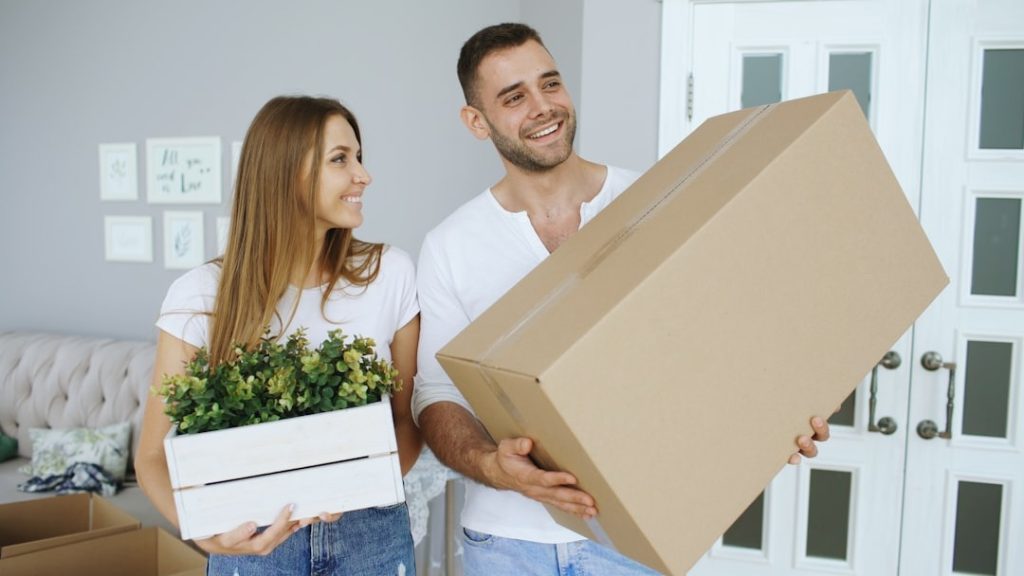 A couple planning a move with boxes and a laptop at home