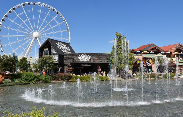 Ole Smoky Moonshine distillery and a large white Ferris wheel behind a dancing water fountain at The Island in Pigeon Forge.