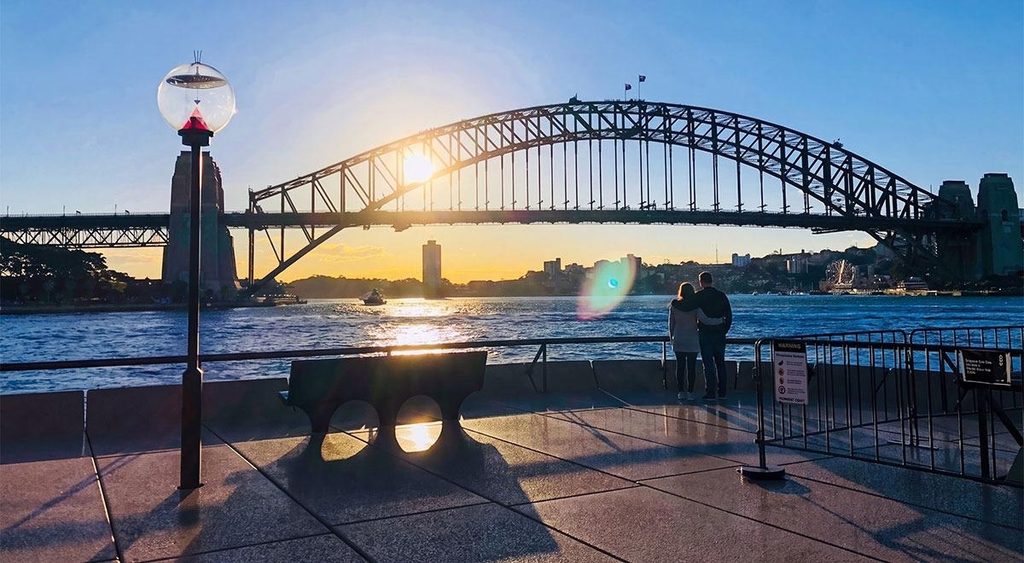 Couple watching the sunset together beside Sydney Harbour with the iconic Harbour Bridge in the background