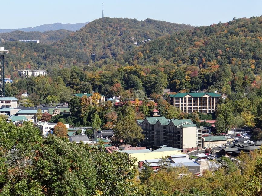 Mountain town with green-roofed resorts nestled in a lush valley surrounded by rolling hills and colorful autumn trees. in Gatlinburg, Tennessee, looking toward the Great Smoky Mountains