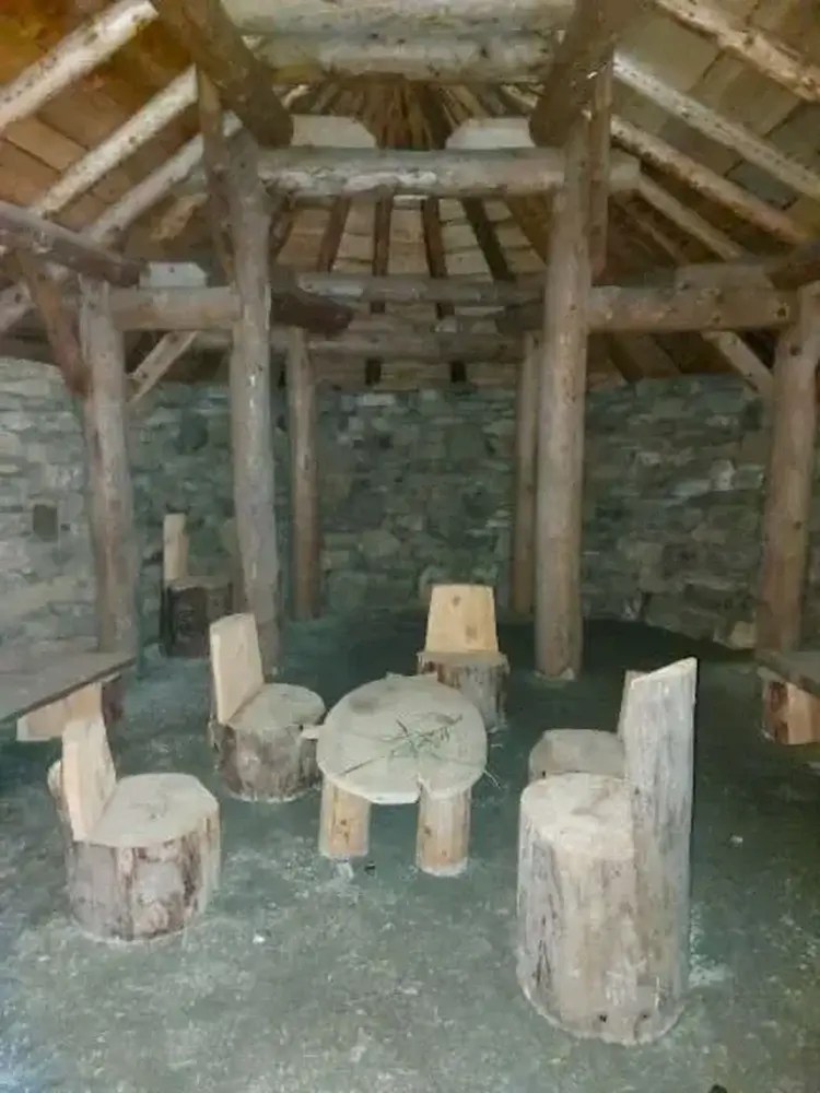 seats made out of tree trunks, inside stone walls and wooden beams of longhouse