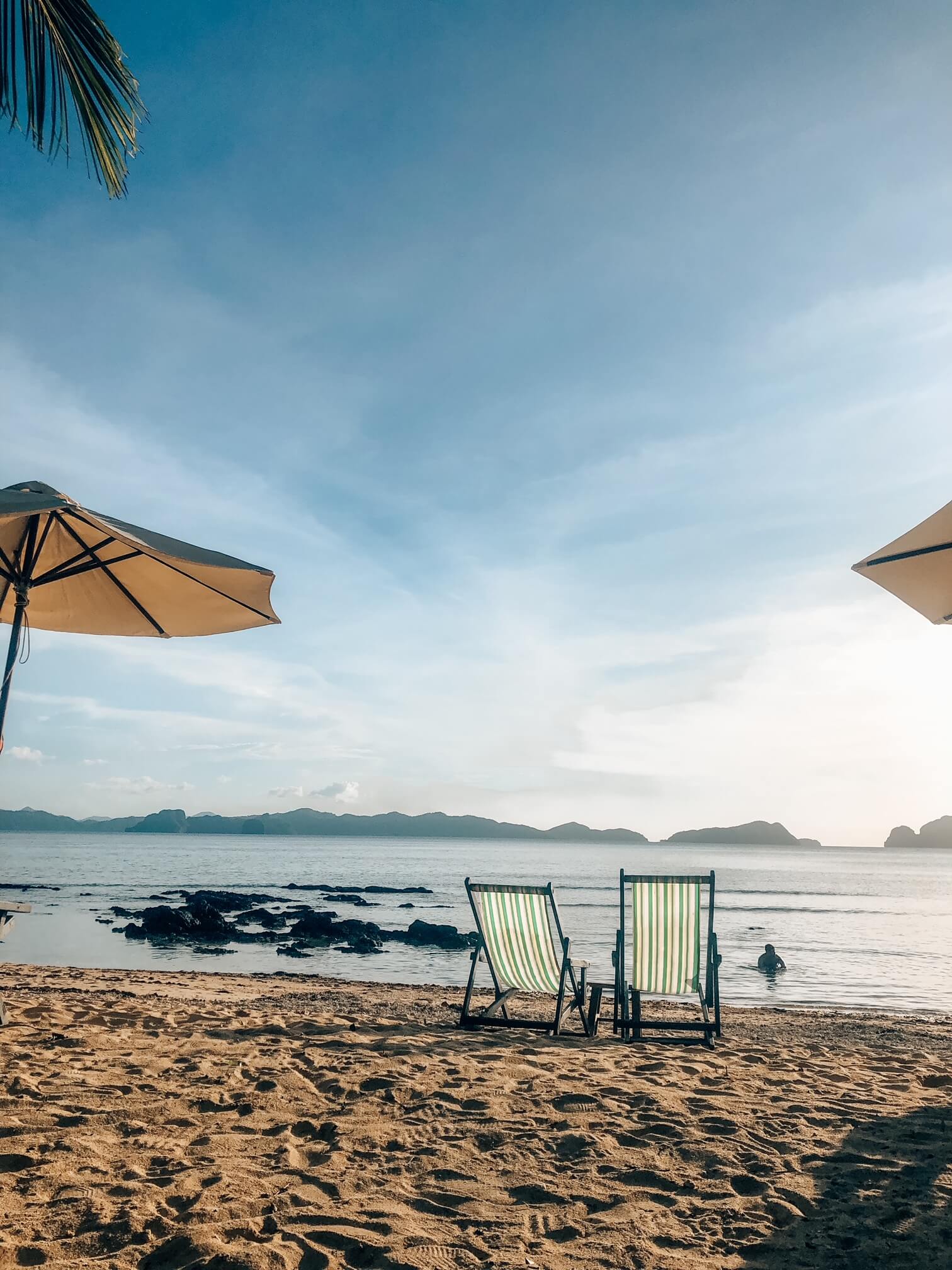 two deck chairs on a beach surrounded by parasols
