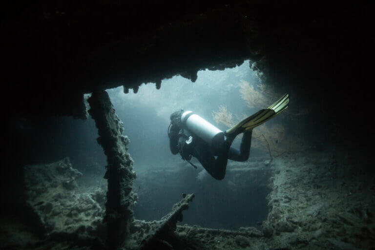 Girl scuba diving inside WW2 Japanese shipwreck in Coron