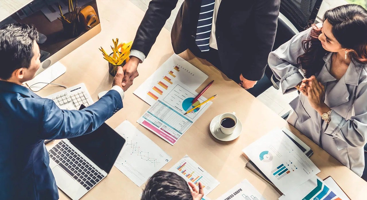 Partners shaking hands in agreement in a rounded table conference