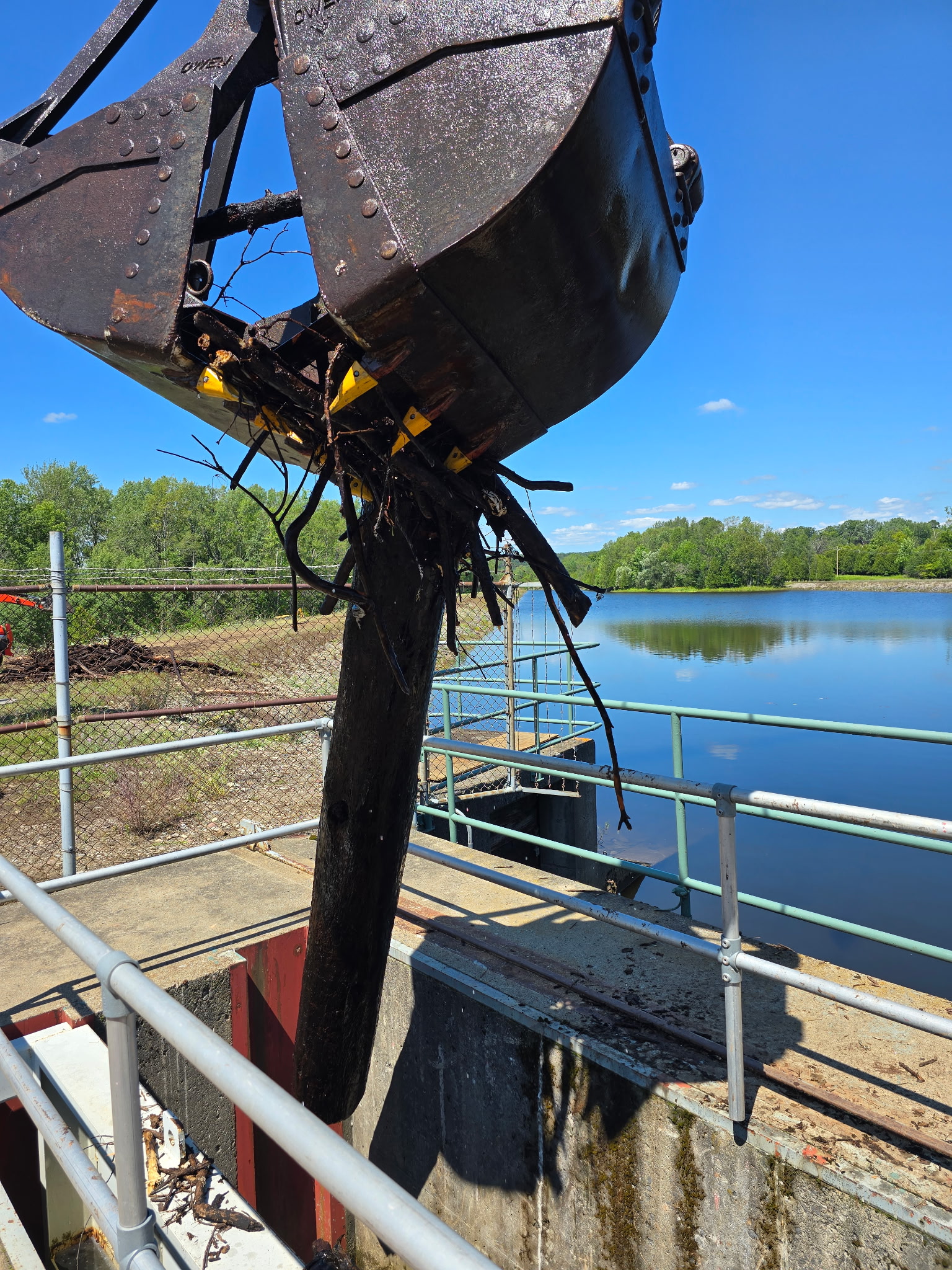 Clamshell bucket suspended from a Trimble Services 80-ton crane during underwater debris removal work in Prospect, New York.