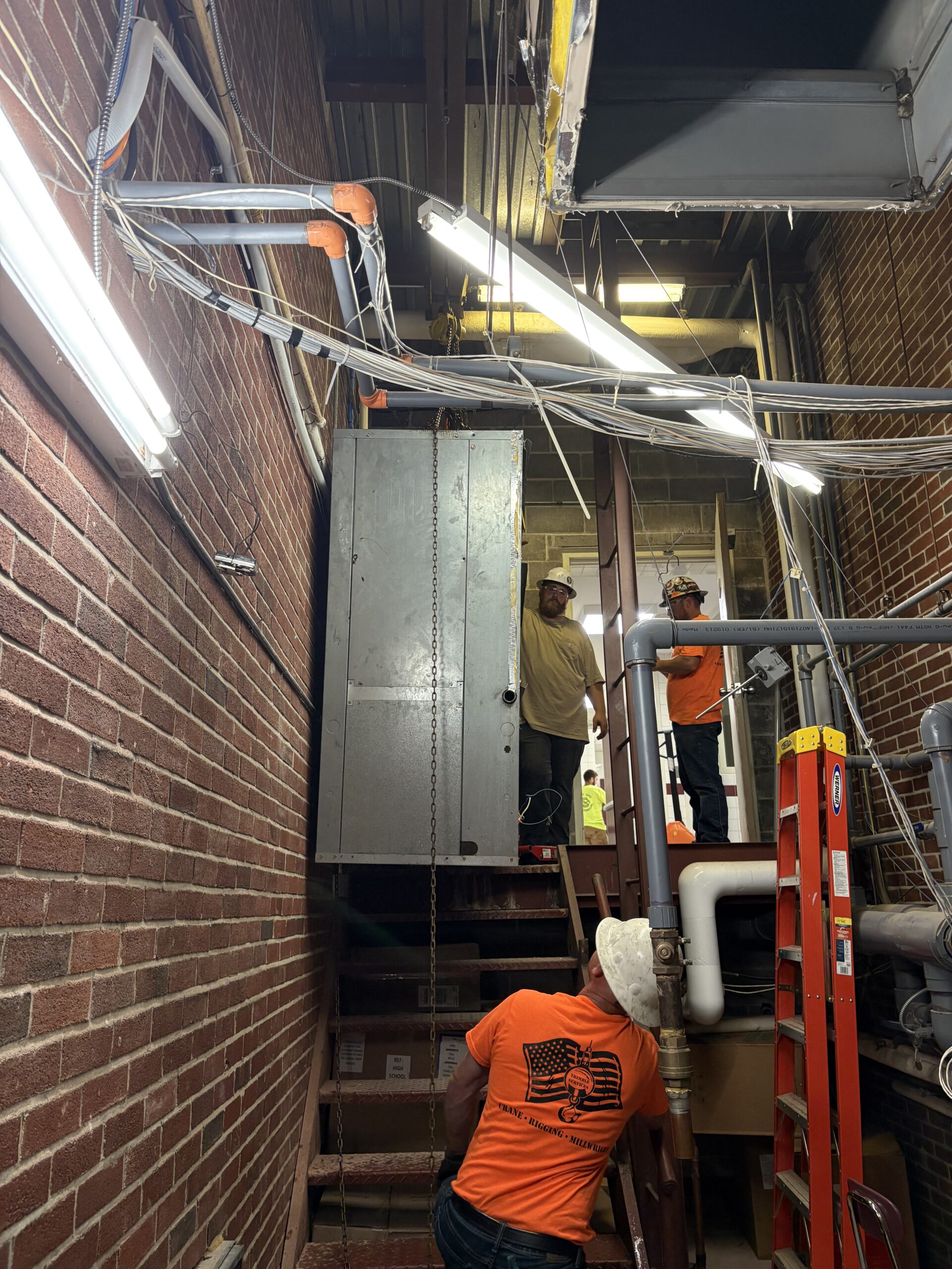 Trimble Services crew hand rigging HVAC equipment through Cazenovia High School.