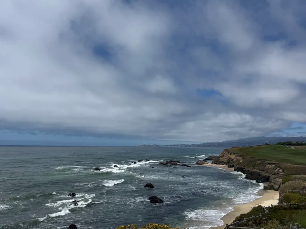 Pacific waves and a sandy cove beneath the coastal cliffs at Half Moon Bay