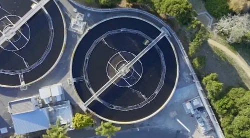 Aerial view of circular water treatment tanks at a facility with a central rotating arm.