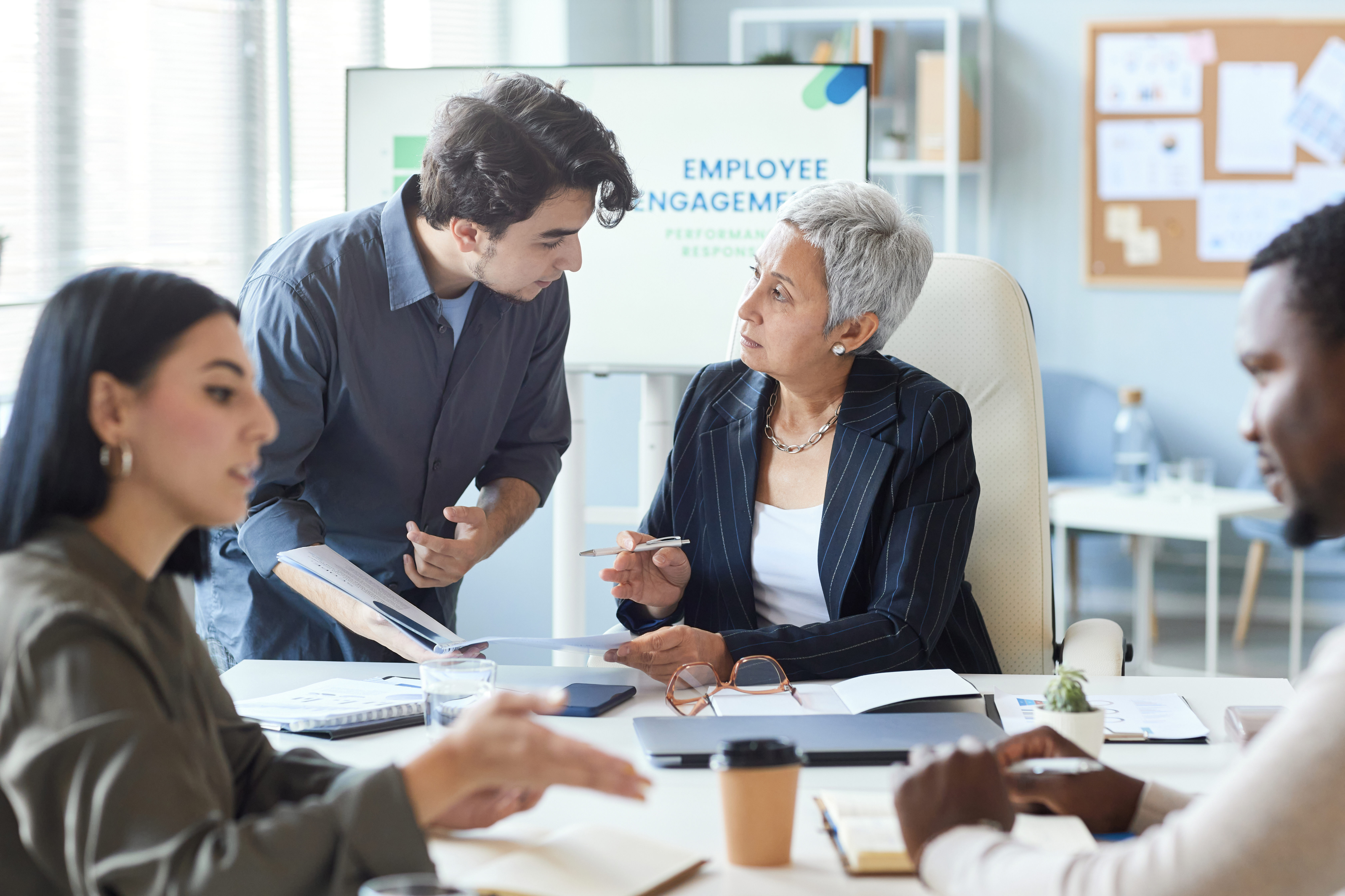 Portrait of senior female boss instructing employee during business meeting in office