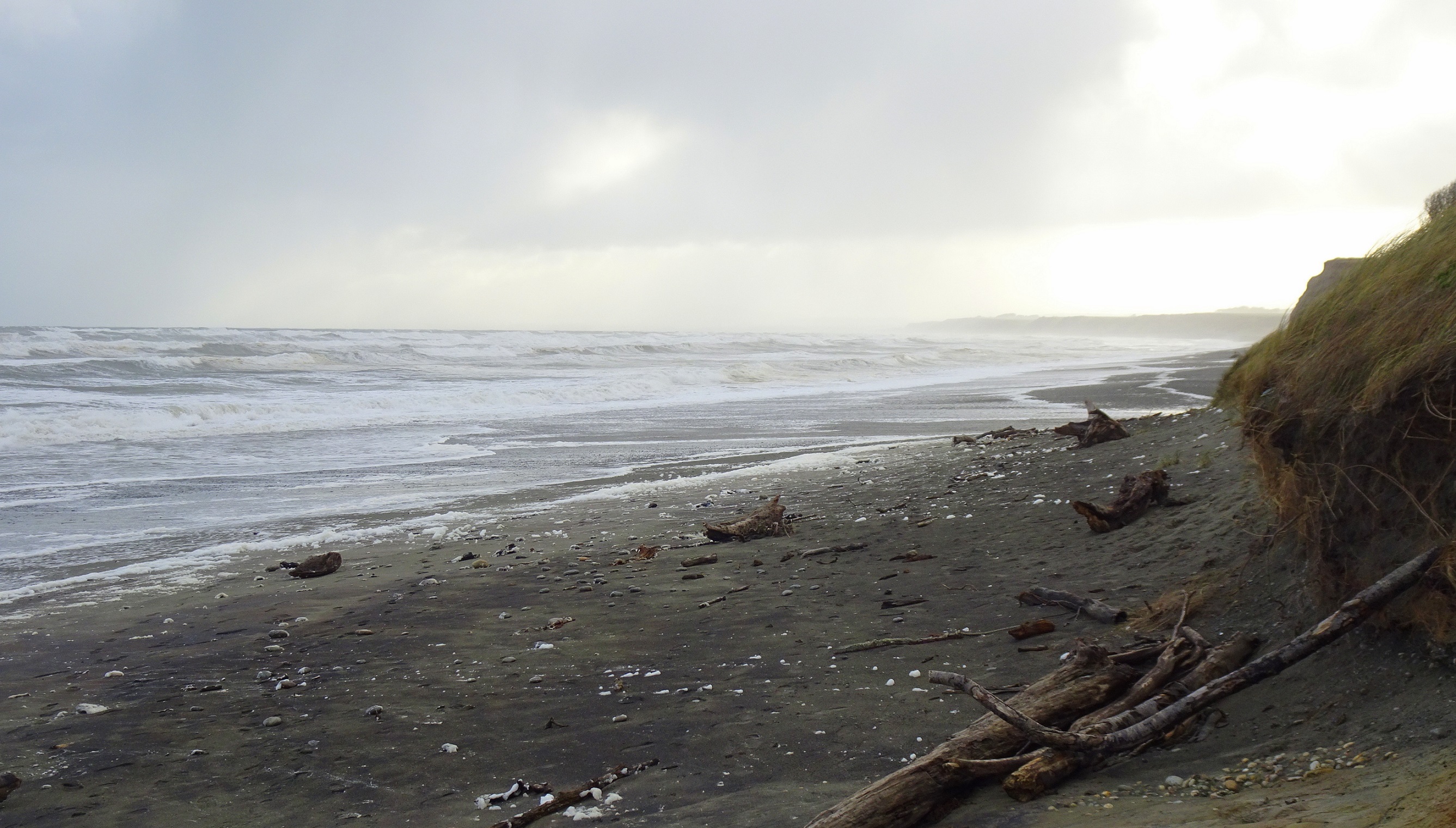 Gemstone Beach in front of the carpark, sea foam being blown around by the wind.
