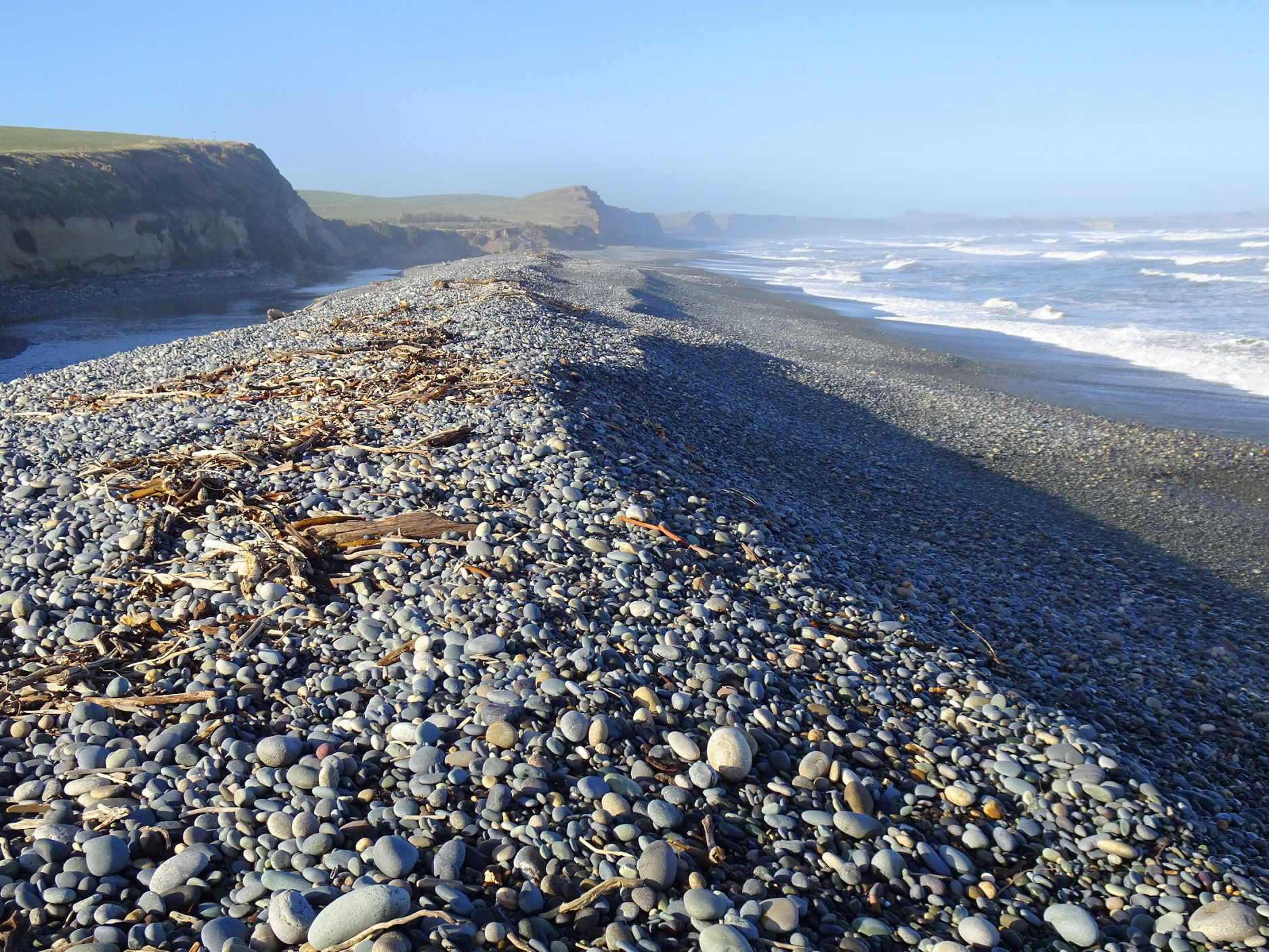 The banks of stones holding back the Waimeamea River lagoon, looking east. The river currently flows across the beach about 300 metres that away.