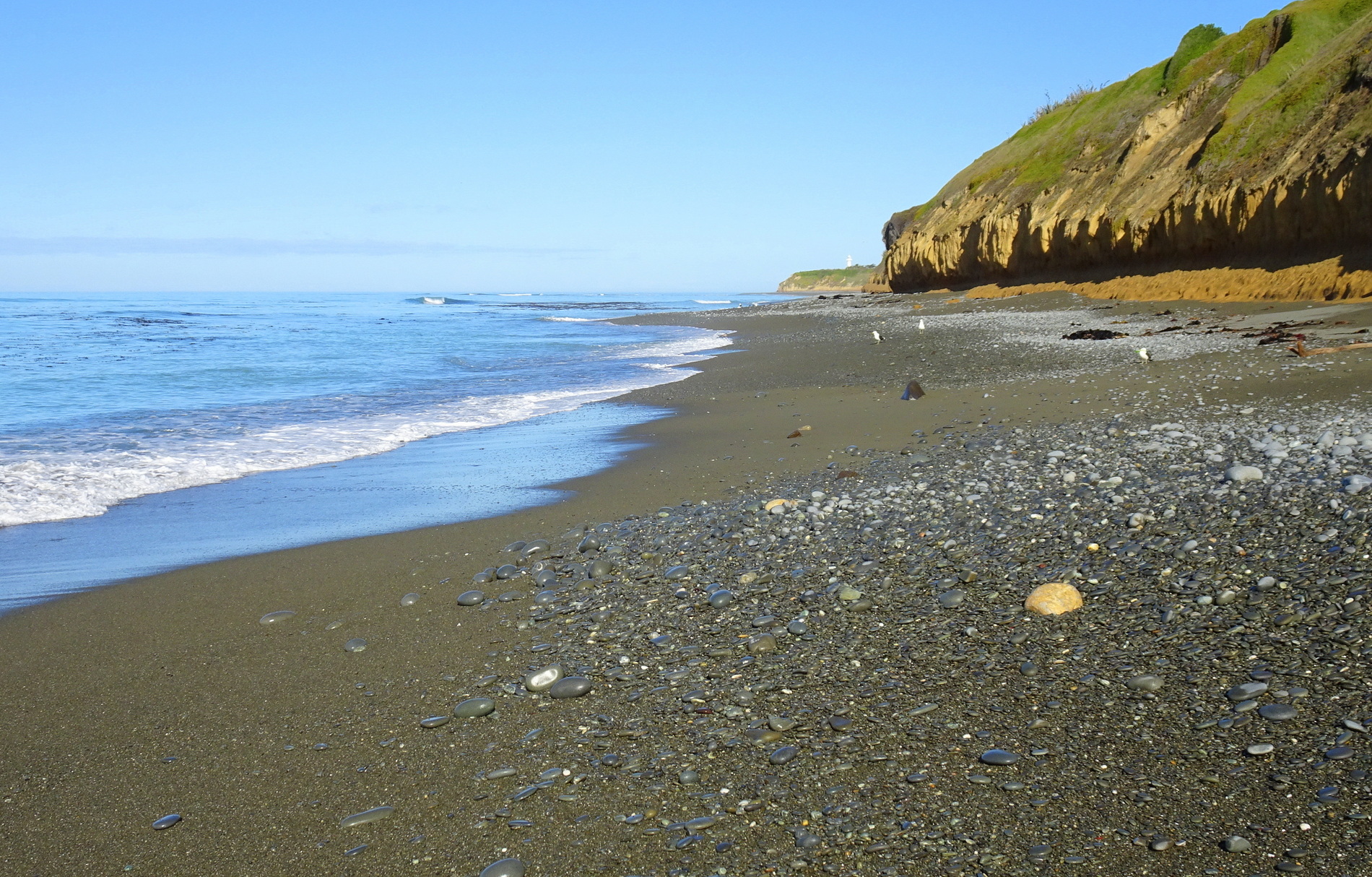 The stretch of beach past Mutu Mutu Point, Jack's Point lighthouse in far distance.