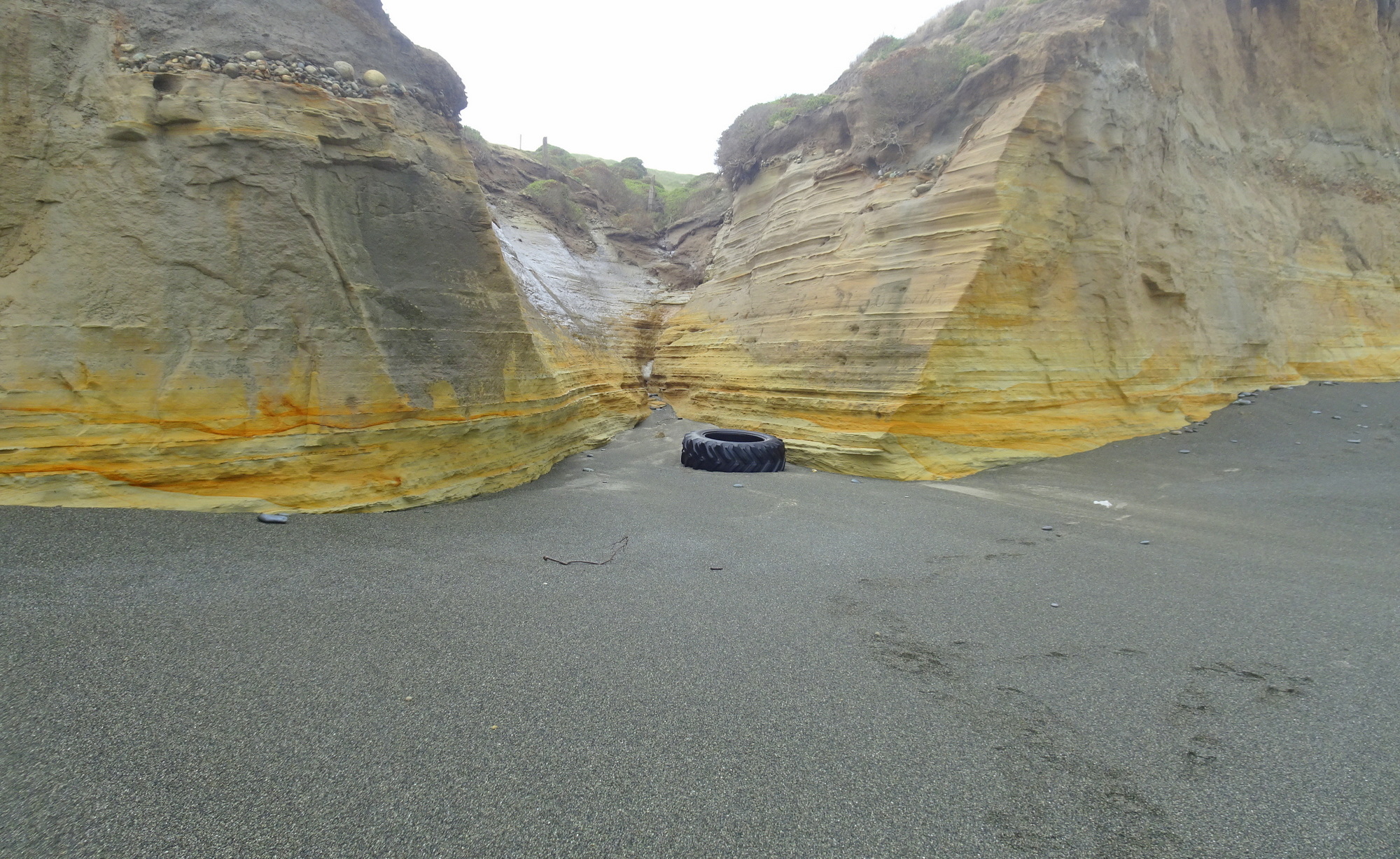 The notch in the cliff, 3/4 along towards the Waimeamea River, with a large tractor tyre washed up.