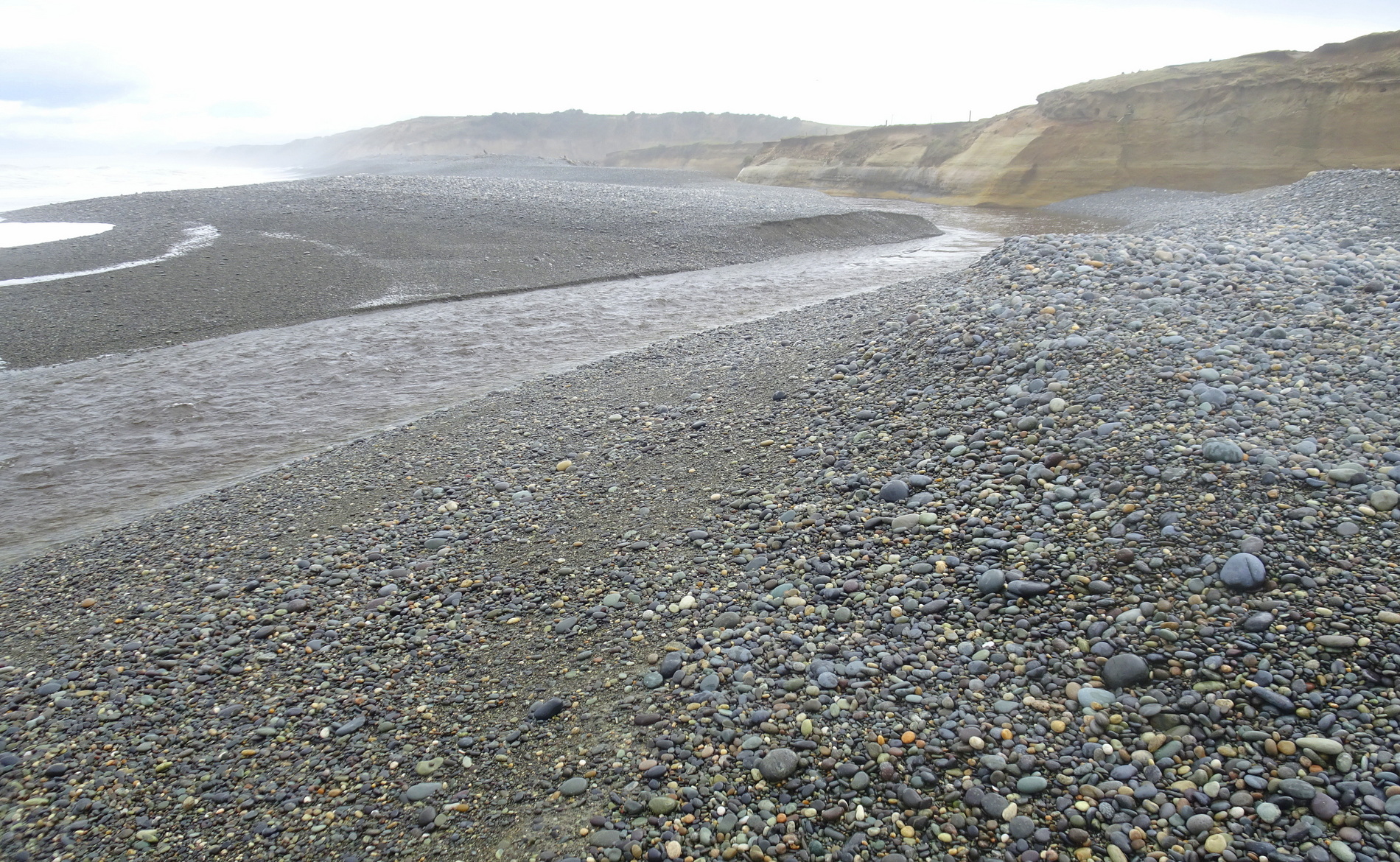 The Waimeamea River flowing across the beach to the sea.