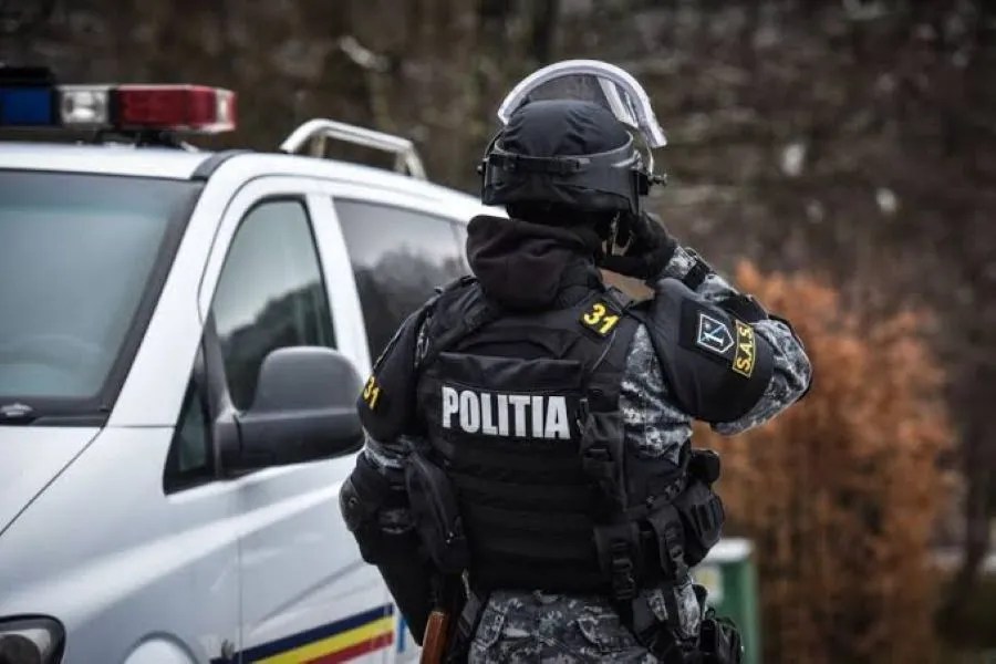 Polițist mascat lângă o autospecială de poliție
