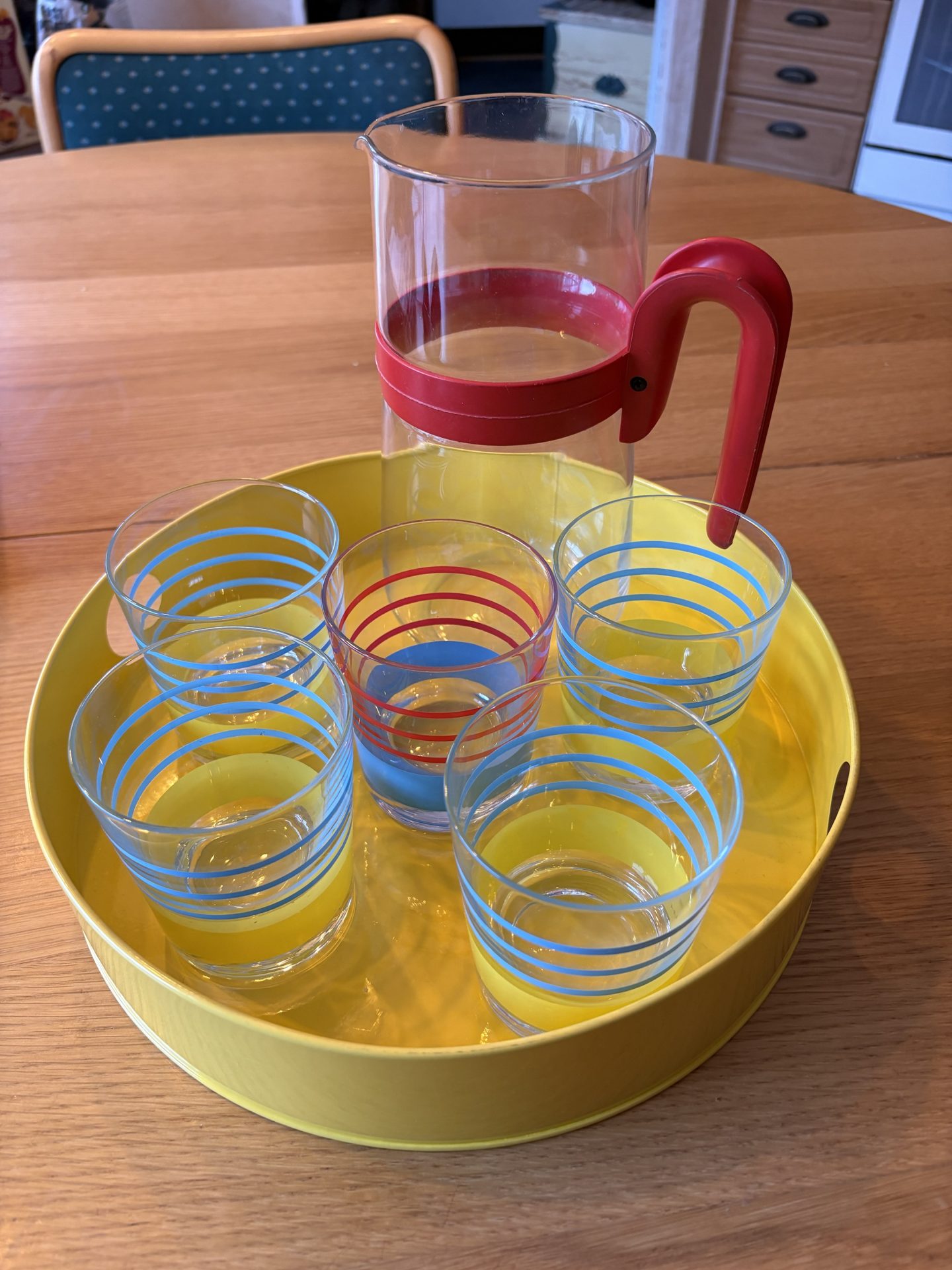 Fem st somriga, färgglada saftglas, tillbringare och bricka i metall i nyskick.
