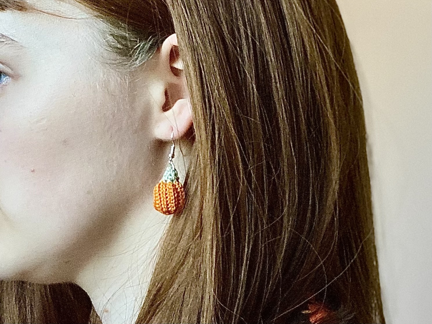 A model wearing crochet pumpkin earrings