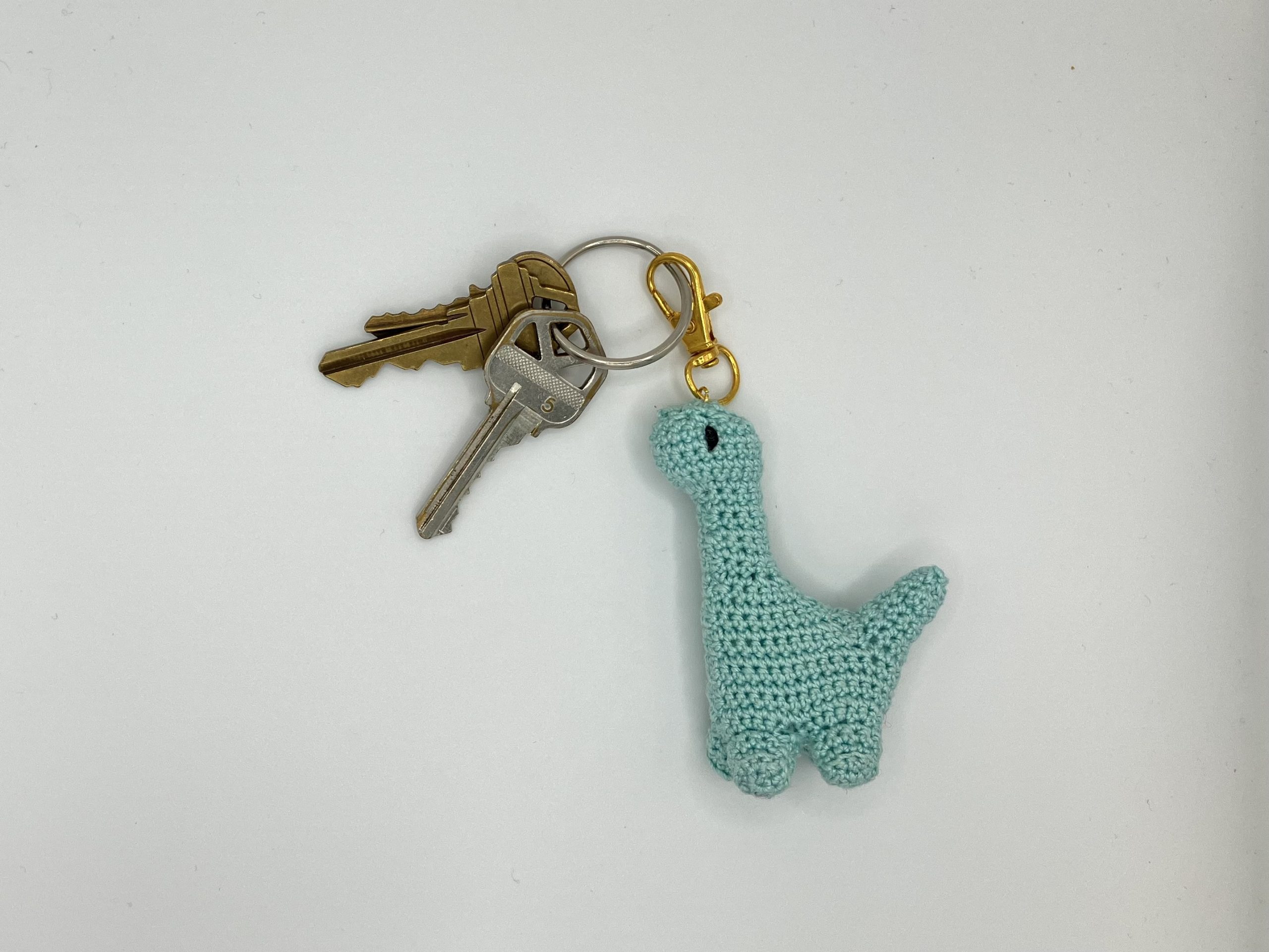 Blue crochet dinosaur keychain on a keyring