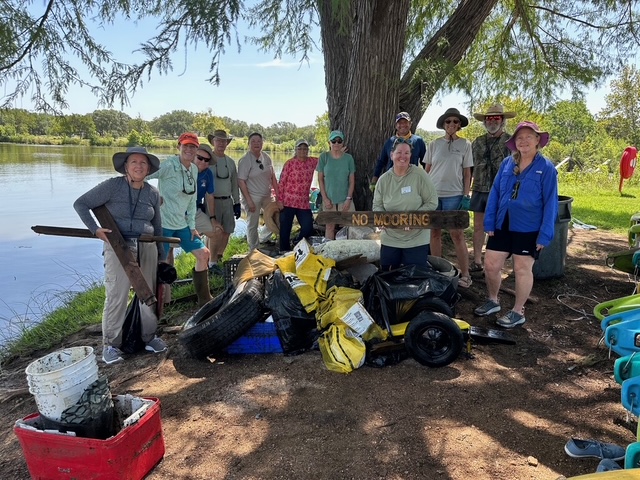 a group of volunteers showing off their trash collected by cleaning up the lake