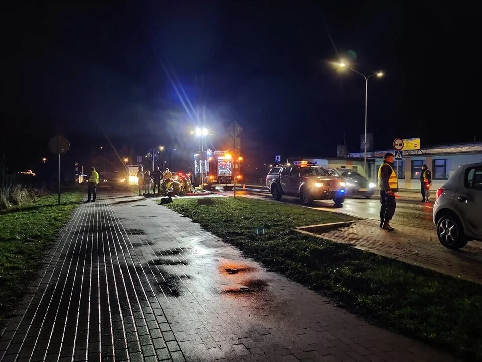 Służby straży pożarnej i straży miejskiej zajmują się potrąconym rowerzystą nad którym klęczy kilku strażaków