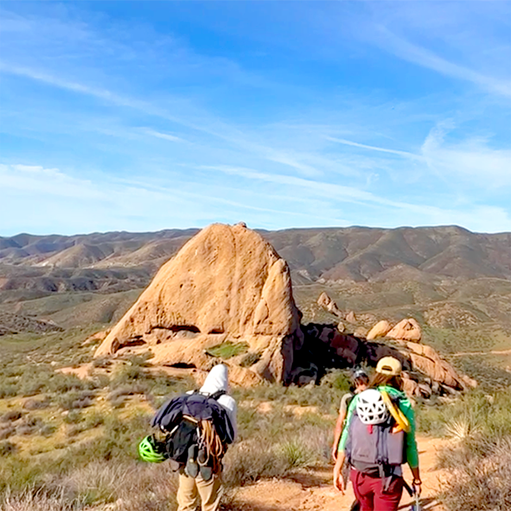 Climbers hiking toward a rock formation near Santa Clarita