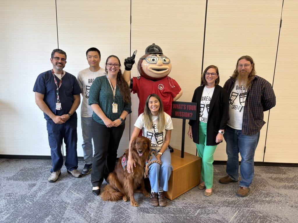 Group of people sitting around Brutus statue with a dog