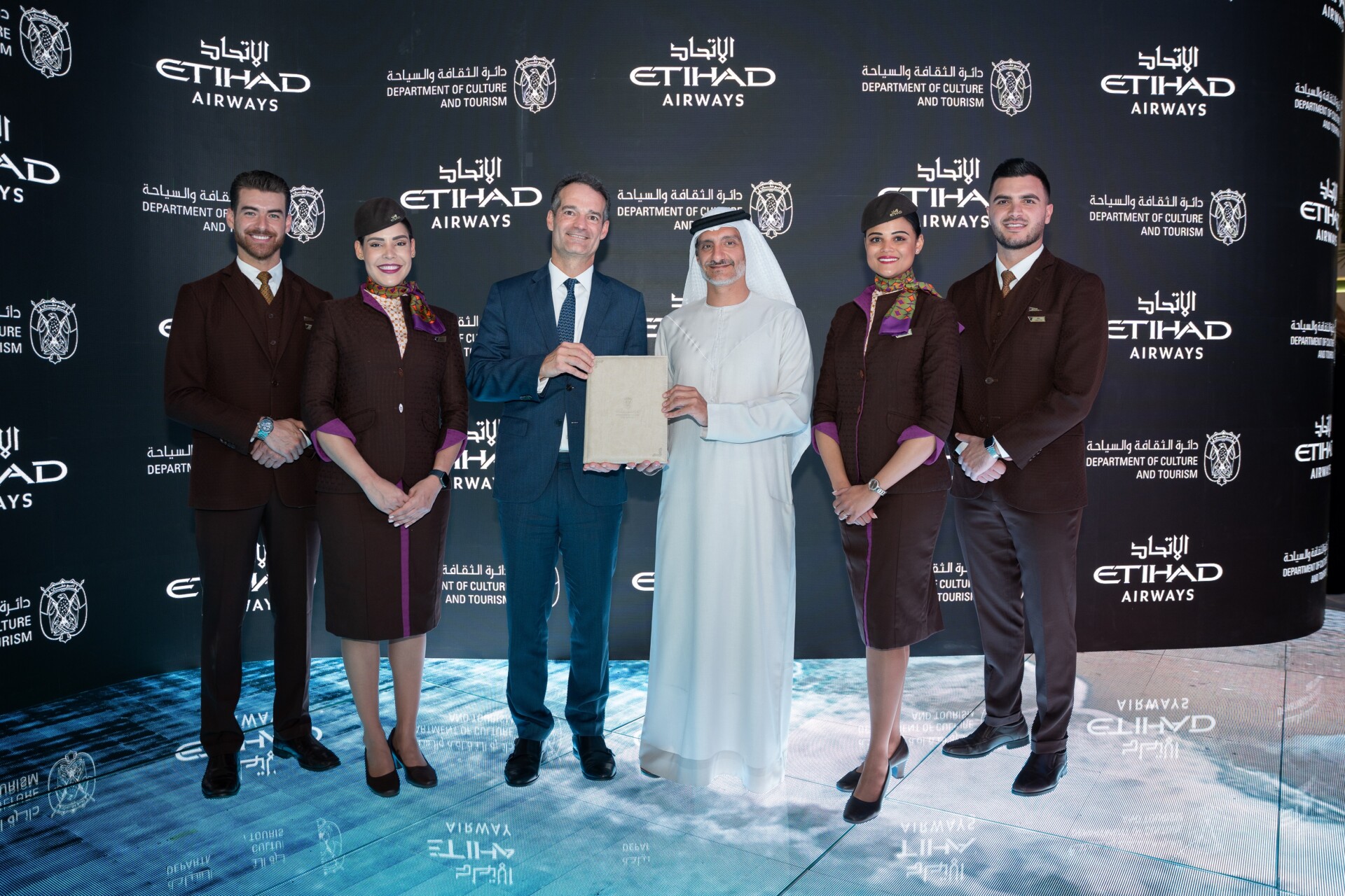 H.E. Saleh Mohamed Al Geziry (centre, right) and Antonoaldo Neves (centre, left) posing with the signed Stopover Abu Dhabi agreement.