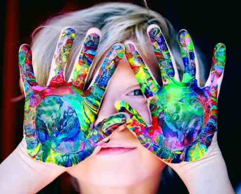 a kid with multicolored hand paint