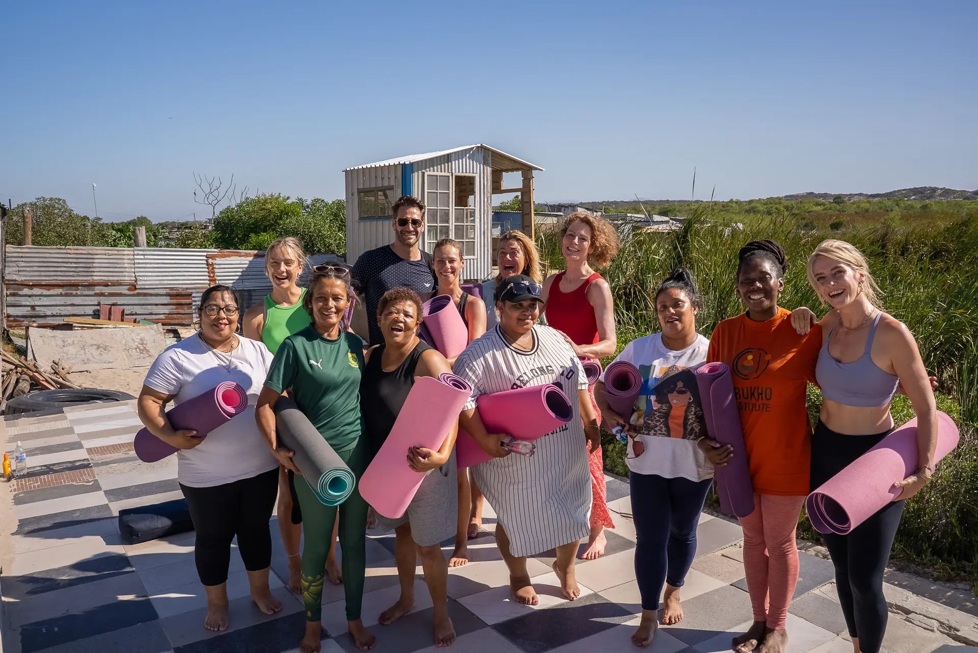 Groep deelnemers met yogamatten, samen buiten na een sessie