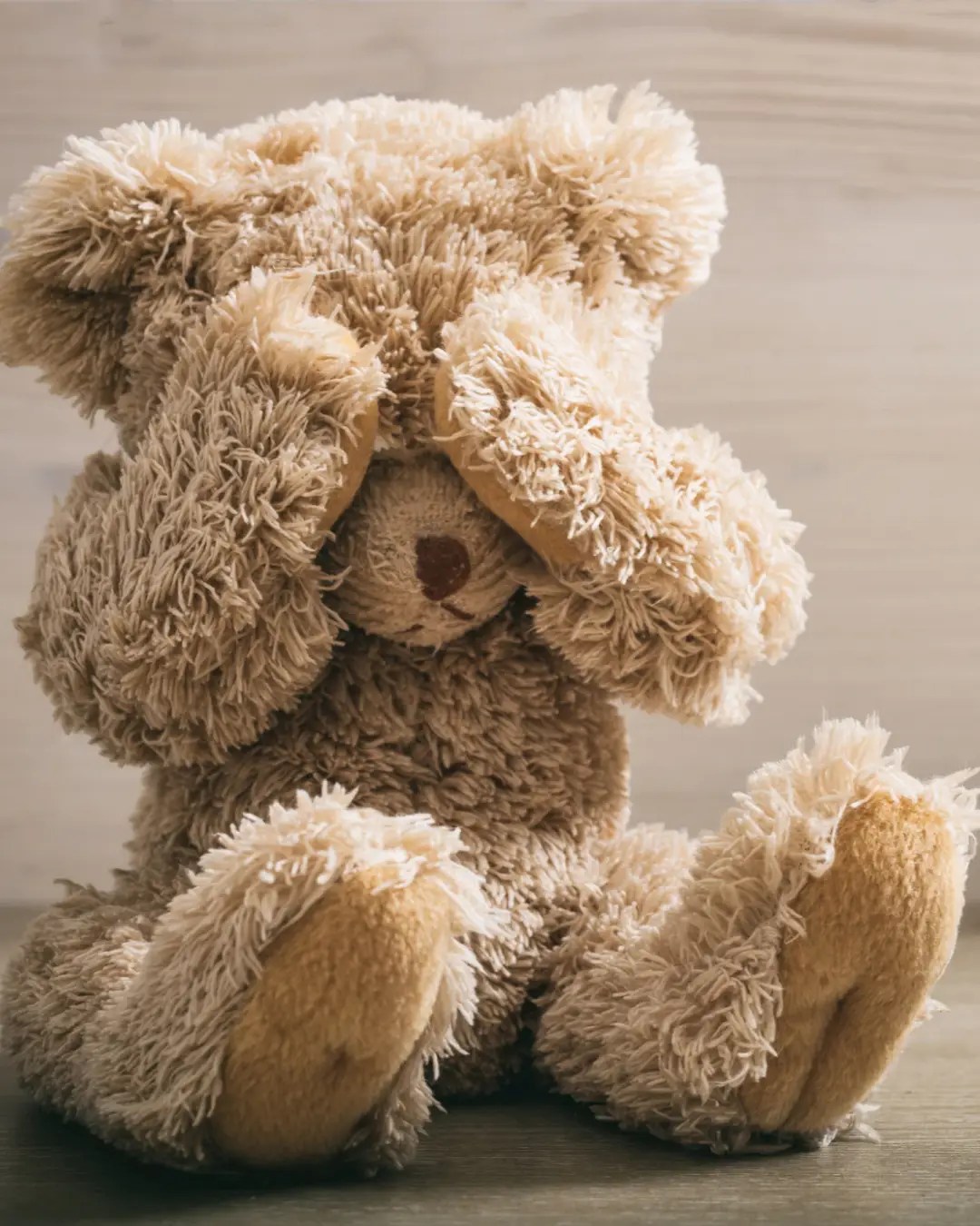 Teddy bear covering its eyes with its paws