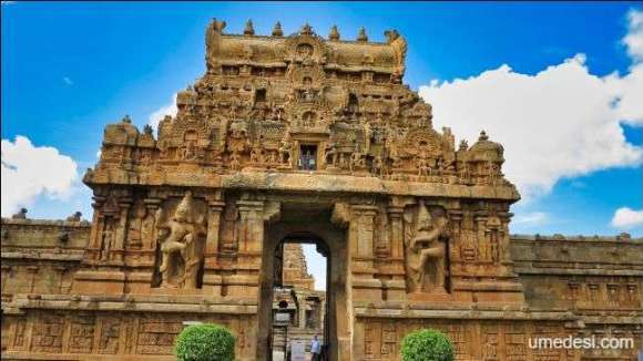 The grand entrance of Brihadeeswara Temple adorned with detailed carvings and sculptures under a clear blue sky.