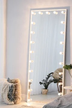 a floor length mirror with lightbulbs framing the mirror