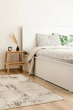 a clean, minimalist style bedroom with a side table and rug