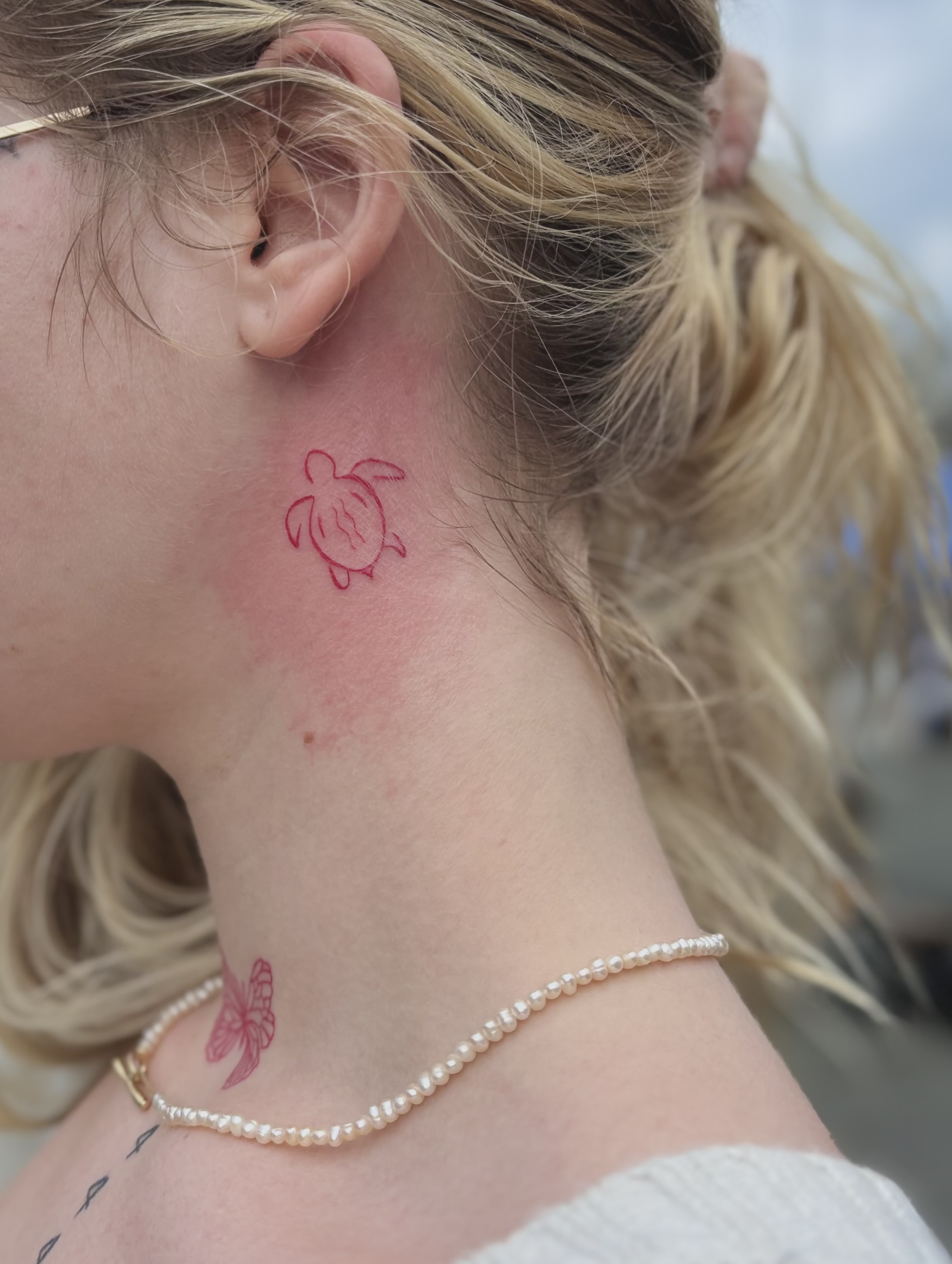 Red small turtle tattoo on neck