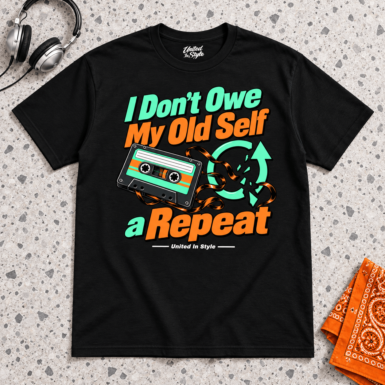 Black I Don’t Owe My Old Self a Repeat T-shirt with mint and tangerine cassette artwork, decorated flatlay by United in Style.