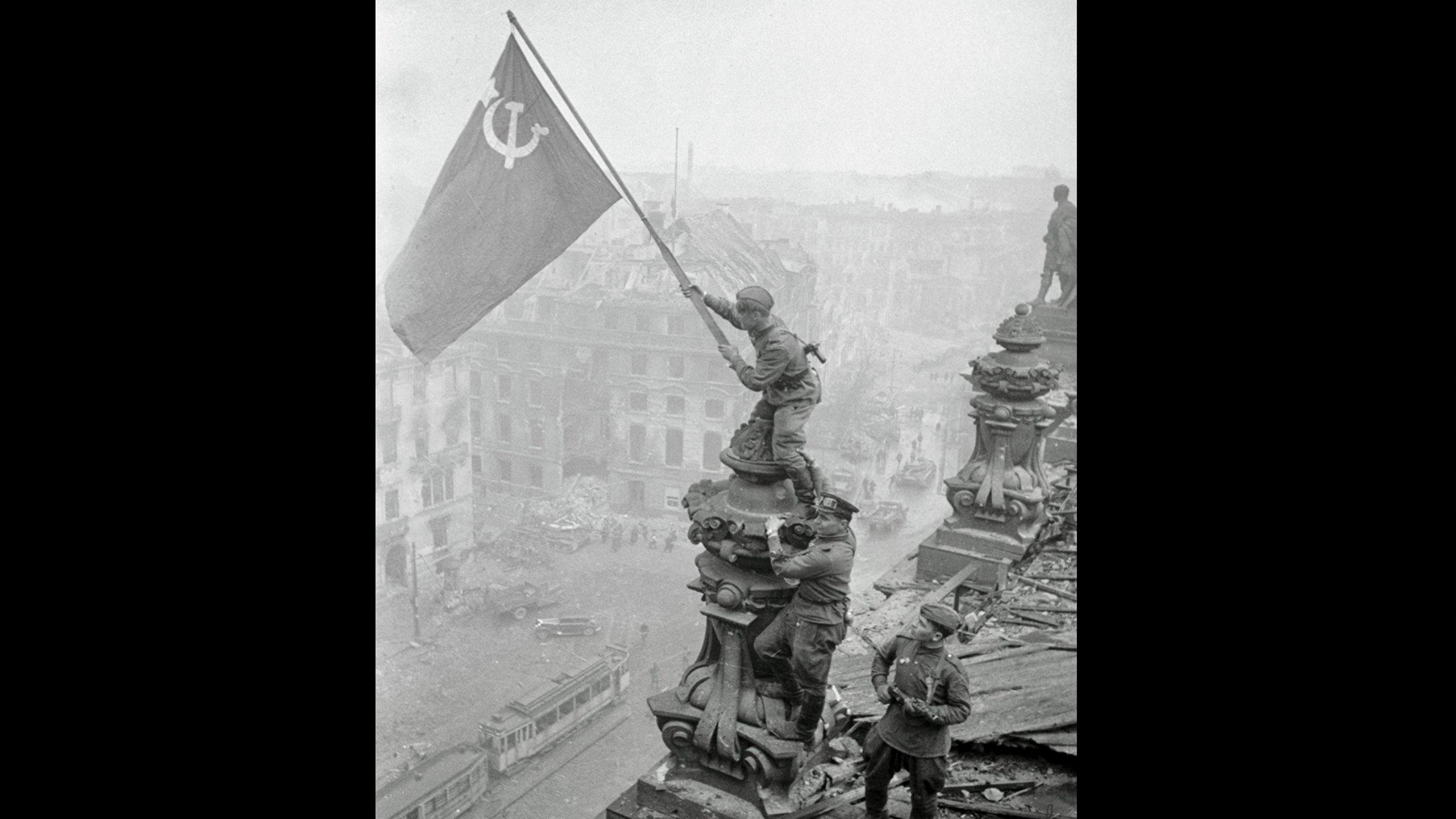 Soviet soldier raising a flag over Berlin during the final days of World War II as the city falls to Soviet forces in 1945