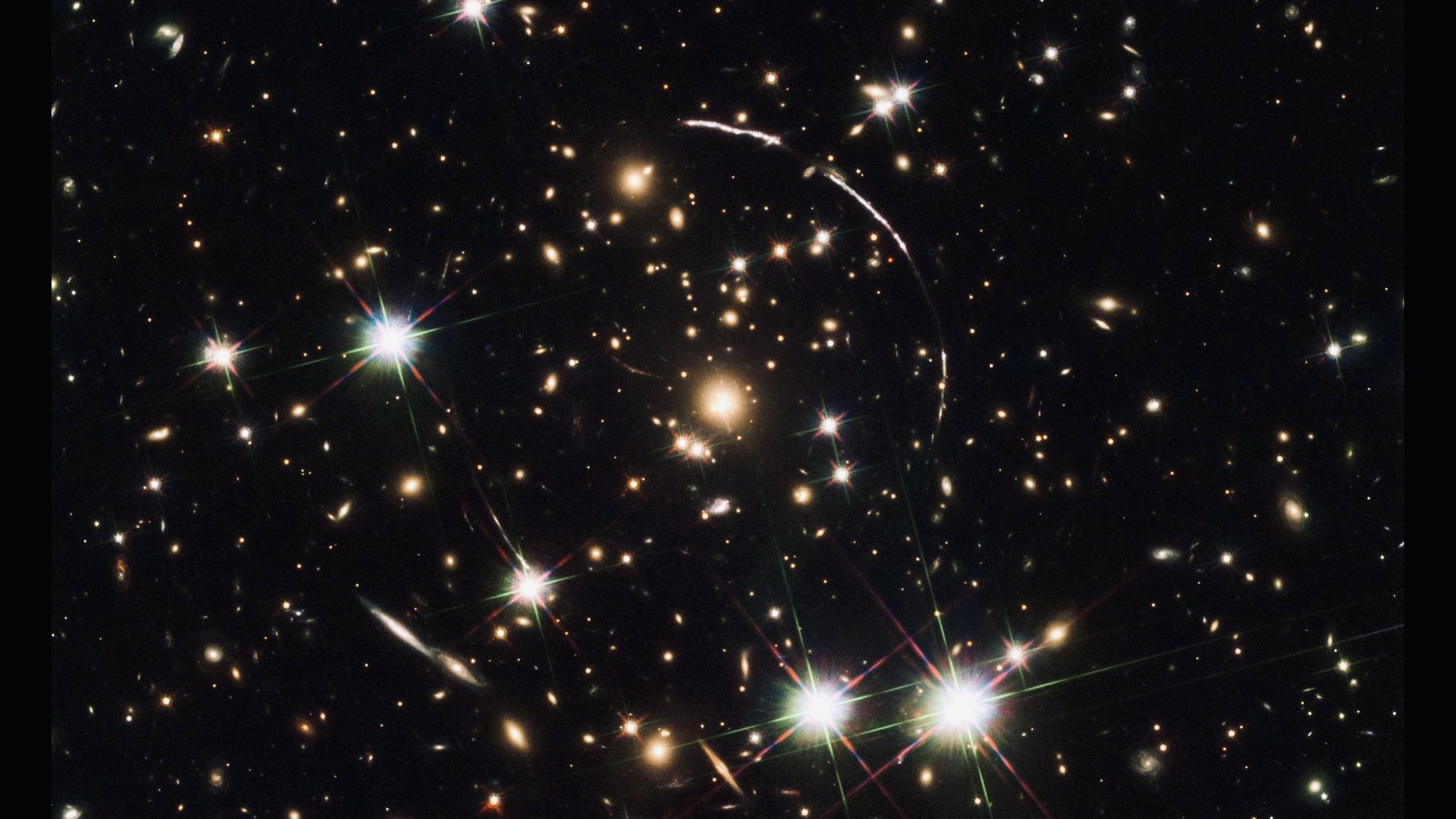 Galaxy cluster showing gravitational lensing arcs bending light from distant objects in deep space