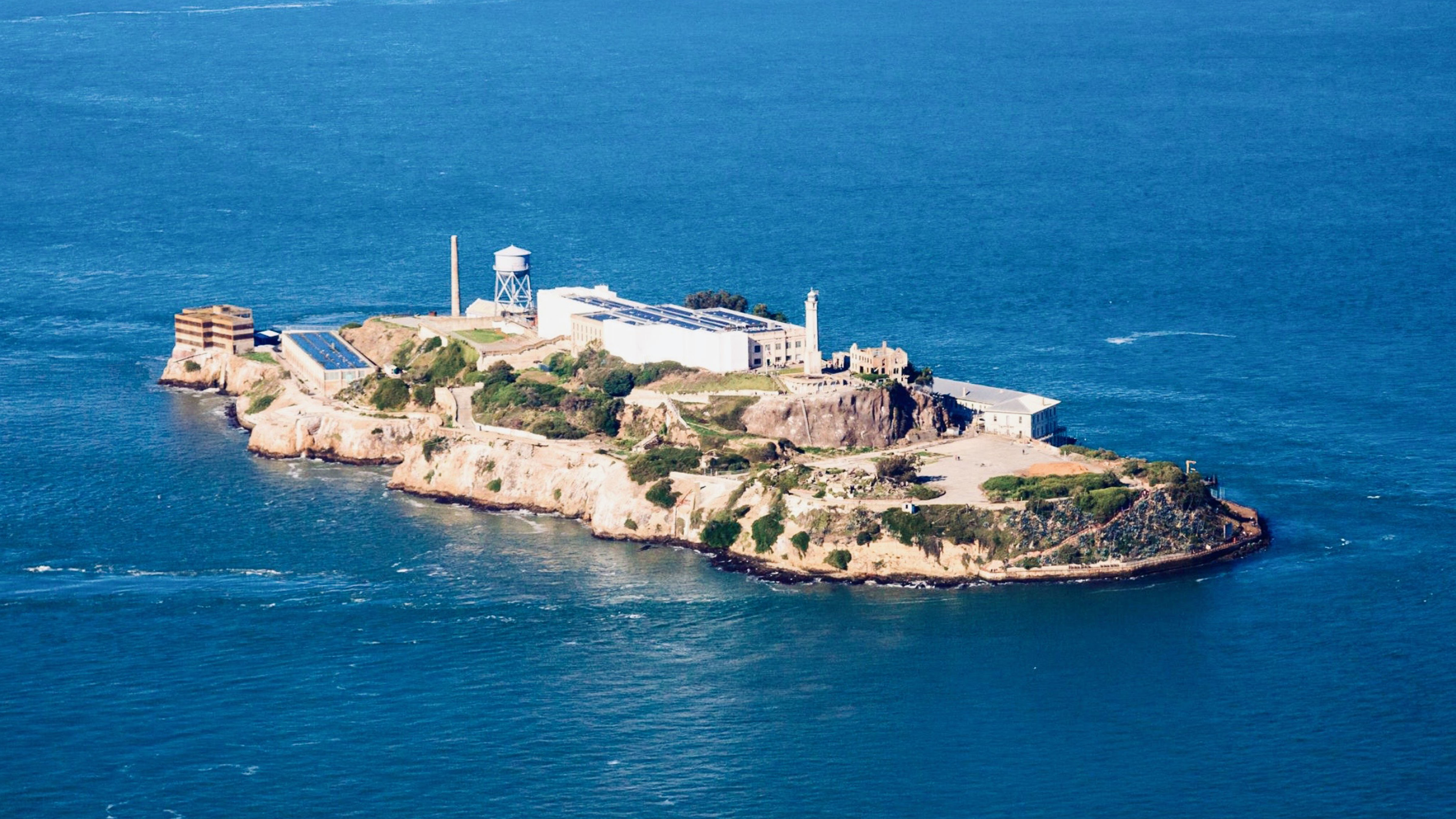 Aerial view of Alcatraz Island in San Francisco Bay, showing the former federal penitentiary surrounded by open water.