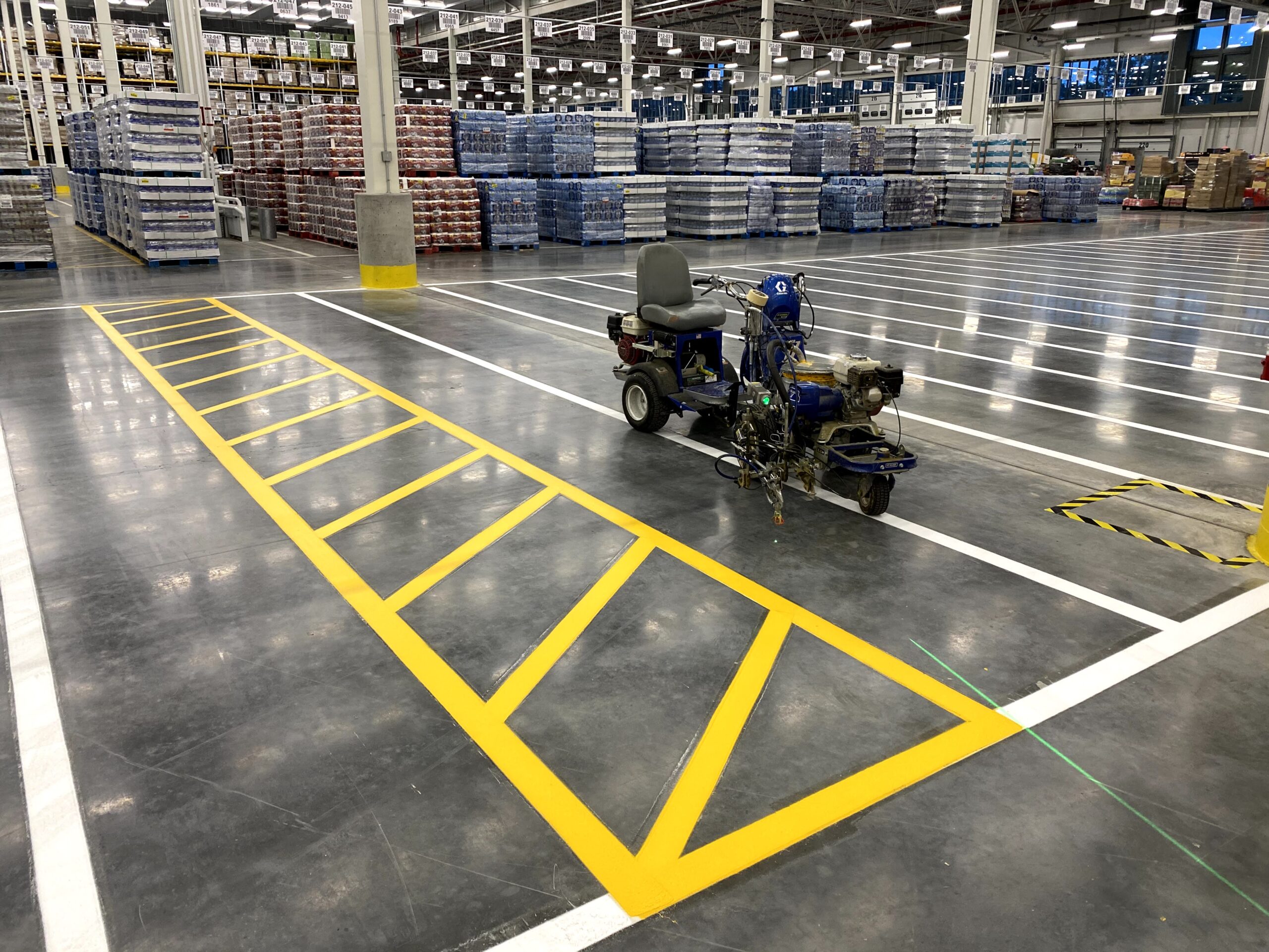 Interior architecture of a Las Vegas warehouse illustrating newly marked bright green lines for designated employee walkways The striping ensures a safe separation between pedestrian areas and heavy machinery operations
